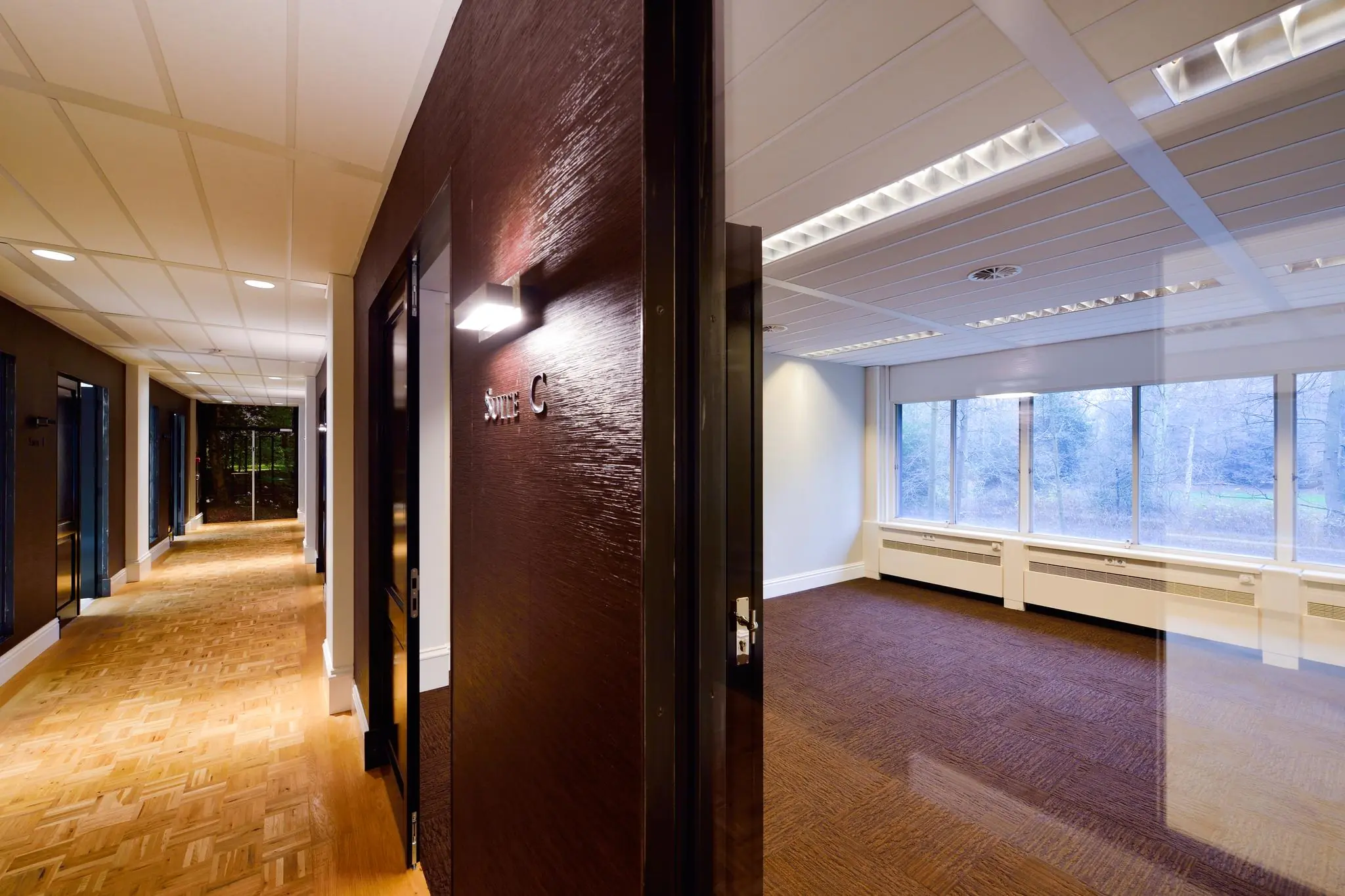 Modern kantoorpand aan de Floris Grijpstraat met zicht op Suite C en een leeg kantoor met grote ramen.